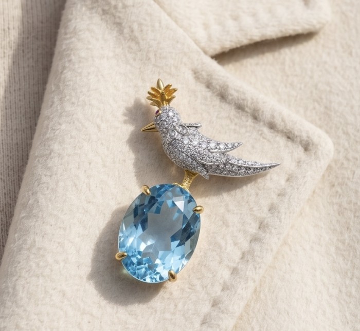 Bird on a Rock - Iconic design- Genuine 28.5 carat Aquamarine 18K Gold over .925 Sterling Silver handmade Pendant - Brooch - Bird on a Rock brooch with aquamarine, angled view on fabric.