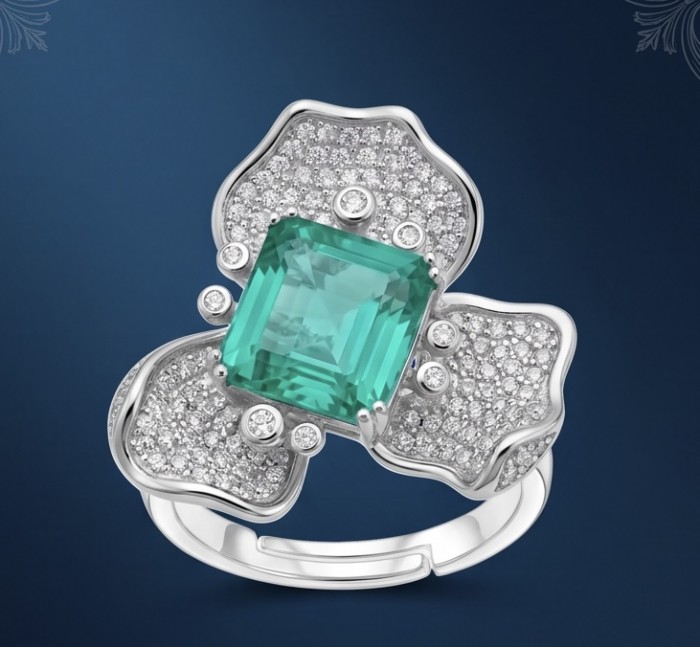 Elizabeth 4.8 carat Colombian Emerald 8.2 carat Moissanite .925 Sterling Silver dipped in Rhodium handcrafted Ring size 7 1/2 - Emerald and moissanite ring on blue background, top view close-up.