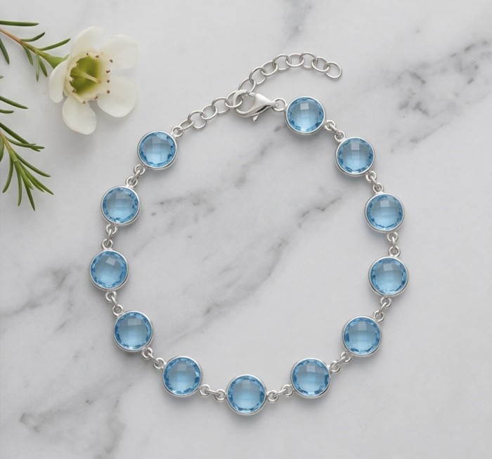 Authentic 10.5 carat Swiss Blue Topaz .925 Sterling Silver handmade Bracelet - Top view of Swiss Blue Topaz bracelet on marble with flower accent.