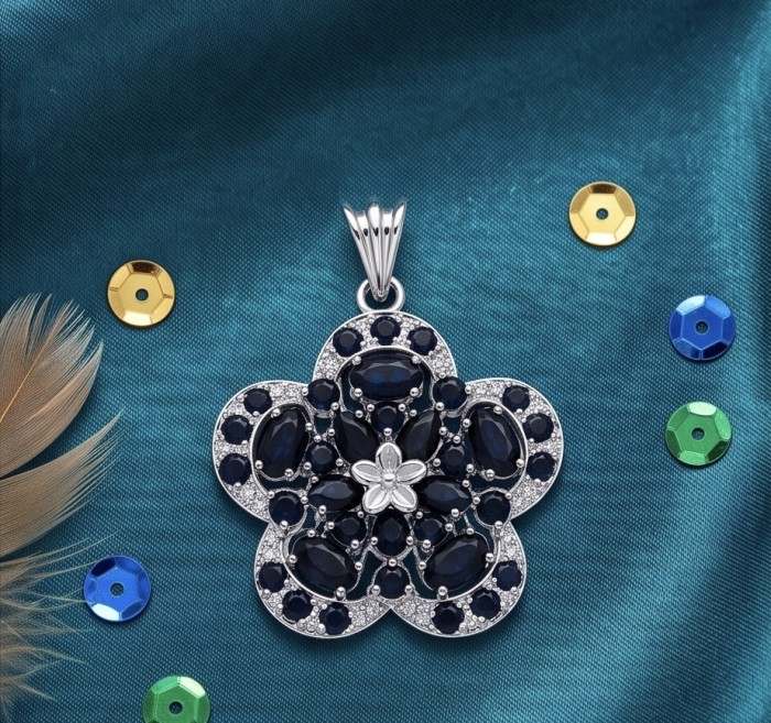 Julietta 12.5 carat genuine Sapphire .925 Sterling Silver dipped in rhodium handmade Pendant - Floral sapphire pendant on teal fabric, top view with sequins.