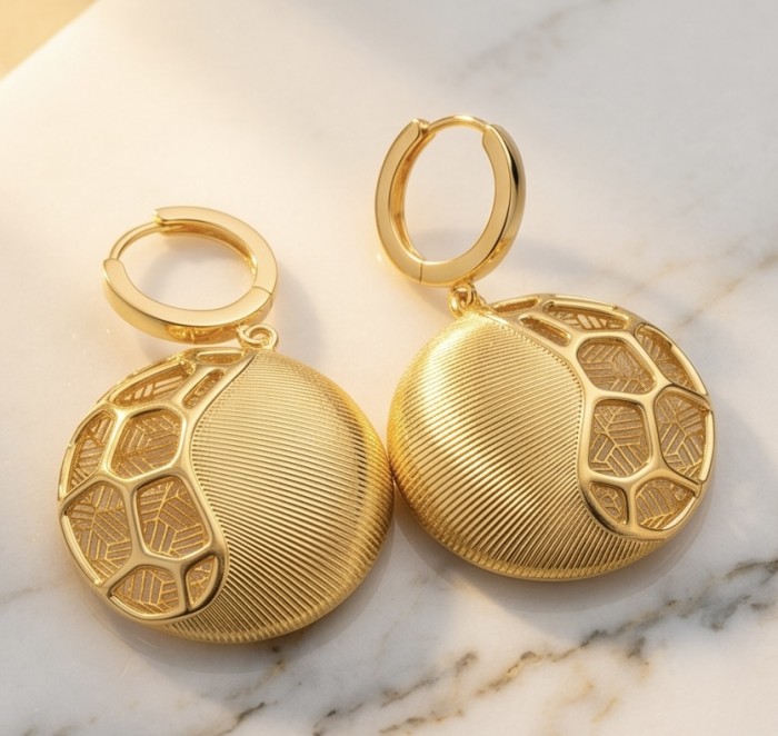Dubai Style - Golden SPHERES .925 Sterling Silver dipped in 22K Gold handmade Large Earrings - Gold round earrings with geometric pattern, top view on marble surface.