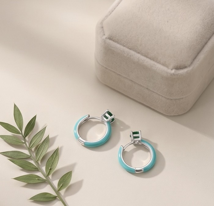 0.5 carat Emerald enamel .925 Sterling Silver handcrafted hoop earrings - Emerald enamel hoop earrings on display with a plant and box.