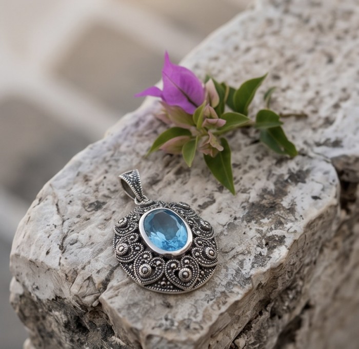 Vintage style 10.8 carat Swiss Blue Topaz .925 Sterling Silver DIPPED IN RHODIUM handmade Pendant - Vintage pendant close-up with blue topaz on stone surface.