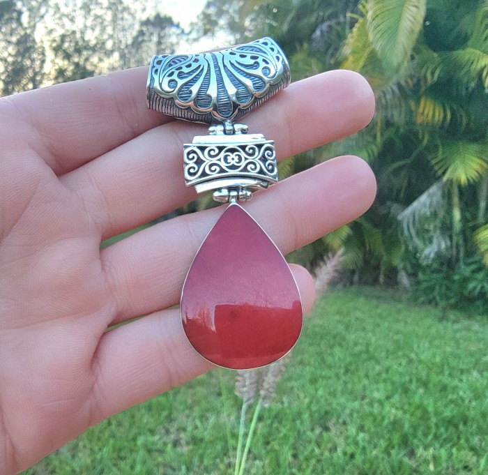Bright Energy Authentic Coral .925 Sterling Silver Bali handmade pendant - Close-up of coral pendant with intricate silver detailing, held in hand.