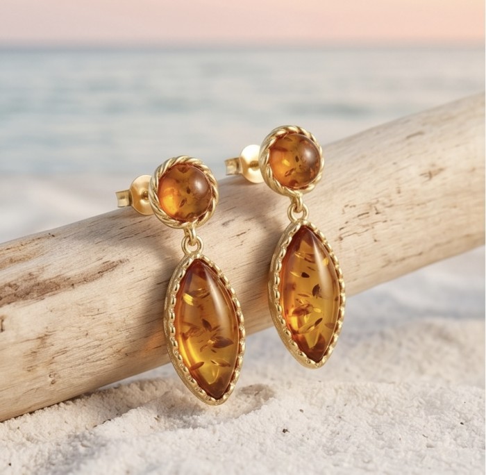 Serenity - Authentic Baltic Amber .925 Sterling Silver handcrafted earrings - Amber earrings on driftwood with beach background, close-up view.