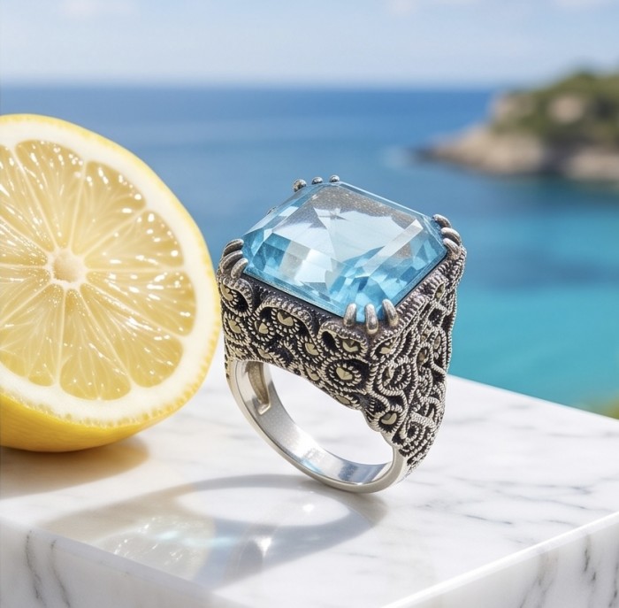 Poseidon 18.8 carat Swiss Blue Topaz .925 Sterling Silver dipped in rhodium handcrafted Large ring size 8 - Close-up of Poseidon blue topaz ring on marble near lemon slice by the sea.