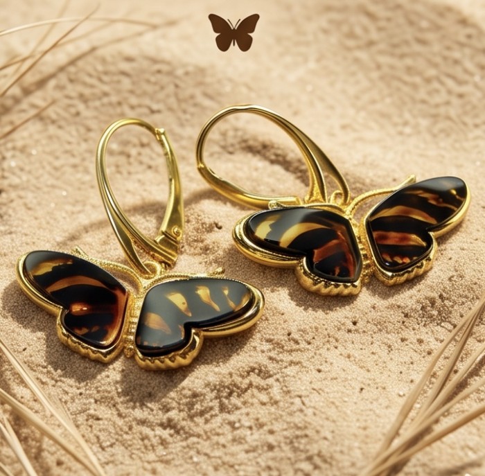 Butterflies carved Baltic Polish Amber 14K Gold over .925 Sterling Silver earrings - Butterfly amber and gold earrings on sand, top view.