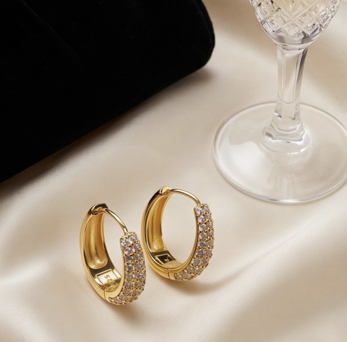 Dubai Style - 0.8 carat White Topaz .925 Sterling Silver dipped in 18K Gold handmade Earrings - Gold hoop earrings on satin, side angle view, near crystal glass.