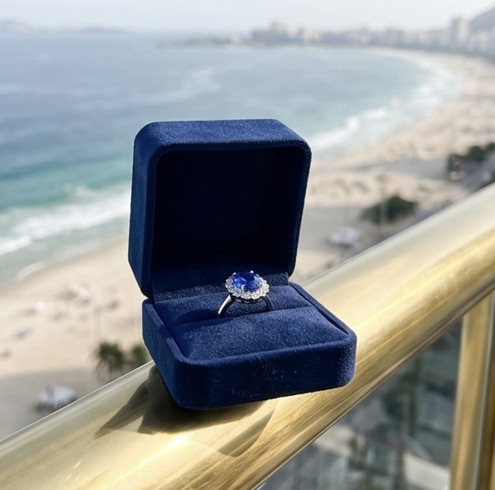 Royalty Design oval cut 24.9 CARAT Tanzanite .925 Sterling Silver Statement Ring s. 9 1/4 - Tanzanite ring in blue box on balcony with beach view, side angle.