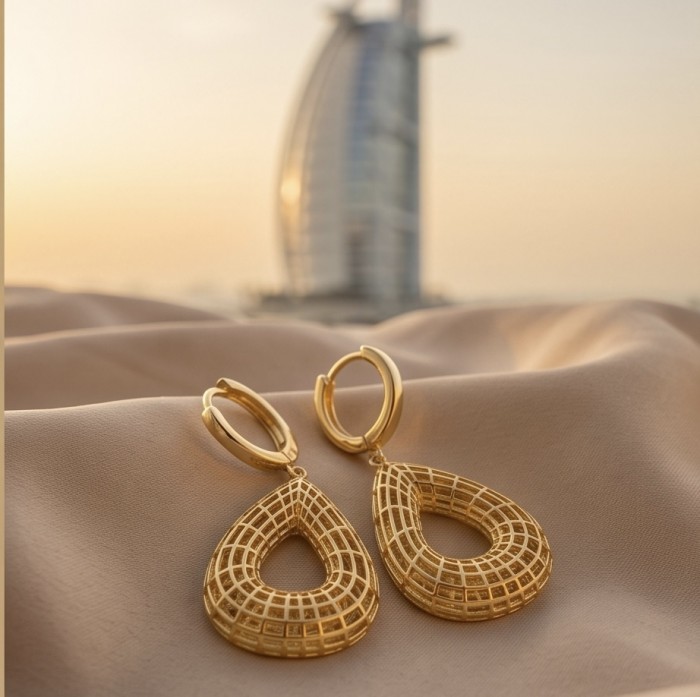 Dubai Style - Golden fancy Drops .925 Sterling Silver dipped in 22K Gold handmade Earrings - Golden drop earrings on fabric with Burj Al Arab background, side view.
