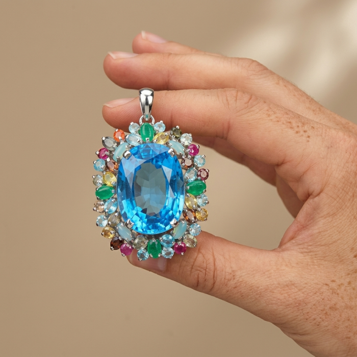 Oceania oval cut 32.8 carat Swiss Blue Topaz .925 Sterling Silver dipped in rhodium Handcrafted Pendant Brooch - Close-up of Oceania 32.8 carat Swiss Blue Topaz pendant held in hand