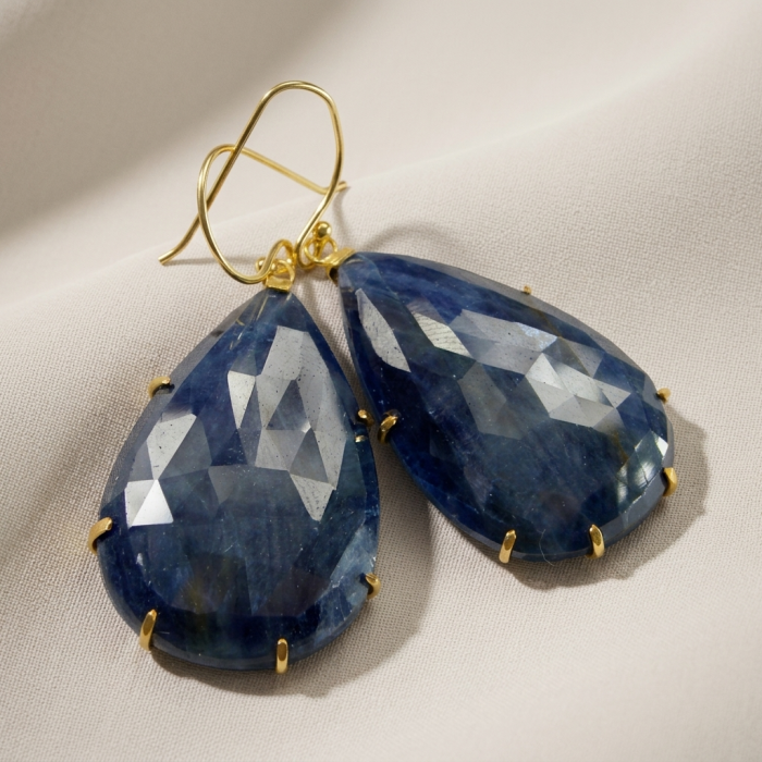 Giovanna - Authentic oval cut 27.9 carat faceted SAPPHIRE .925 Sterling Silver handcrafted earrings - Close-up of faceted sapphire teardrop earrings on white fabric.
