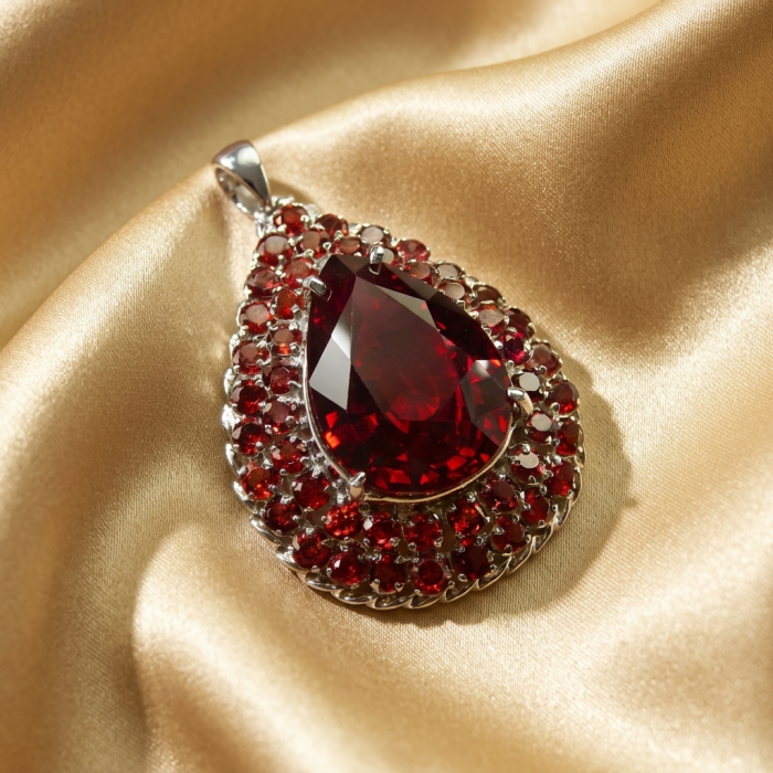 Rare finding! 27.2 carat authentic Kashmir Ruby rhodium over .925 Sterling Silver handmade Statement Pendant Brooch - Close-up of a teardrop-shaped Kashmir Ruby pendant on satin fabric