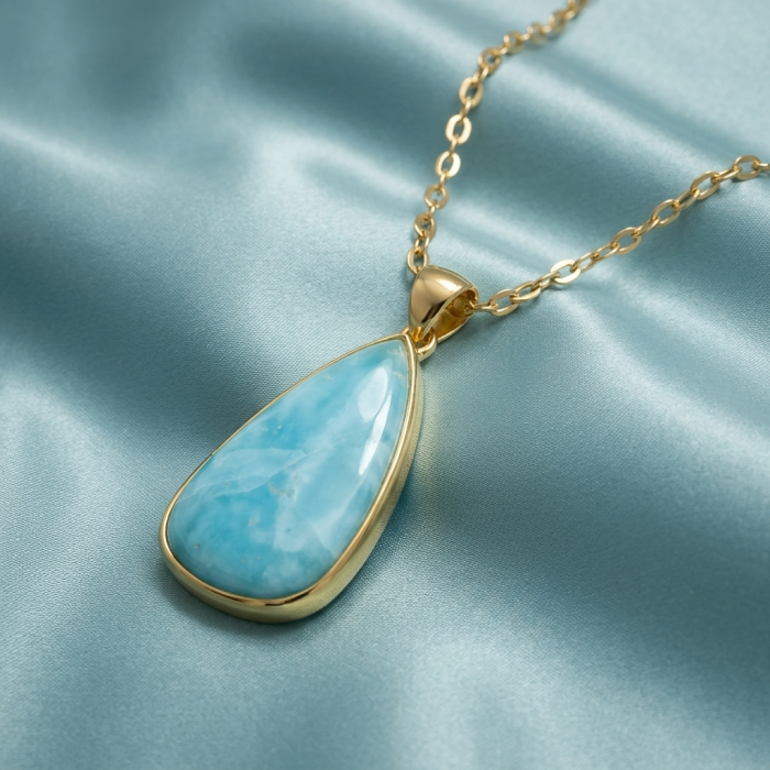 Best quality 58.5 carat Authentic Caribbean Larimar 22K Gold over .925 Sterling Silver handmade pendant - Larimar pendant on gold chain, close-up on fabric background.