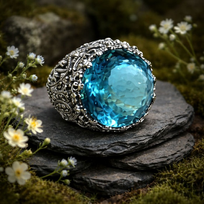 Massive Deep Blue 28.9 carat natural Aquamarine .925 Sterling Silver handcrafted Large ring size 8 - Close-up of ornate aquamarine ring on stone surface with flowers.