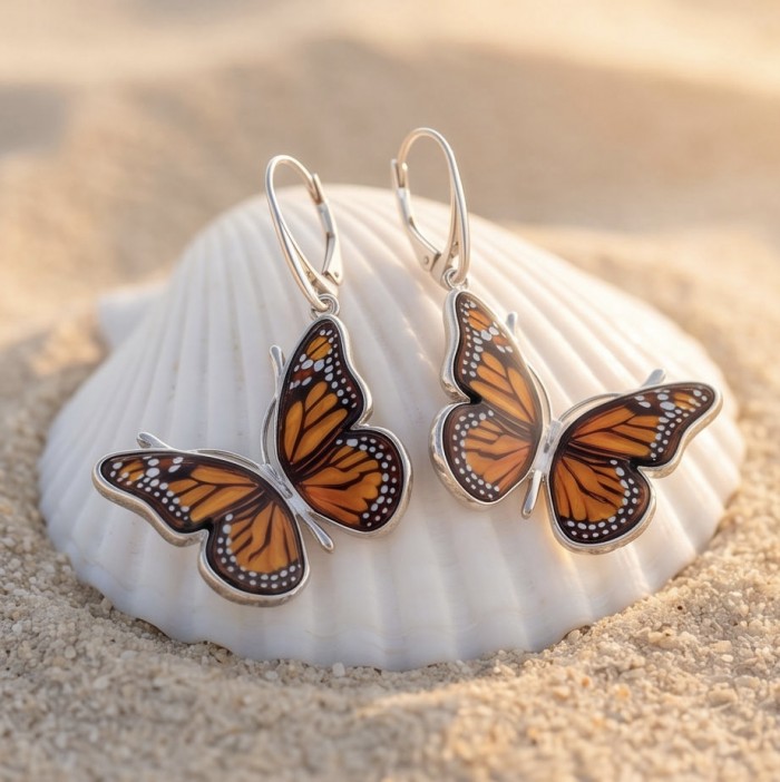 Butterflies carved Baltic Polish Amber 18K Gold over .925 Sterling Silver handcrafted earrings - Butterfly amber earrings on seashell, front view, on sandy background.