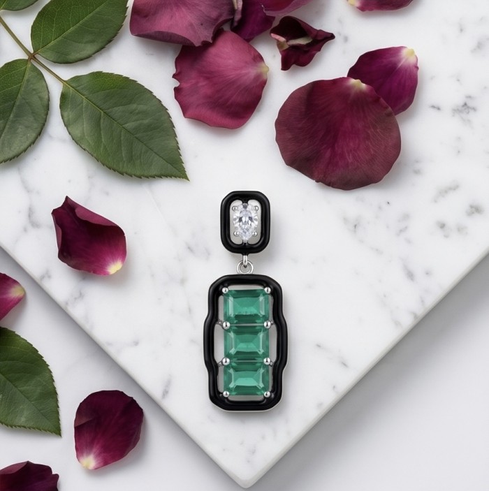 Art Deco 9.5 carat Emerald black enamel .925 Sterling Silver handmade Pendant - Emerald earrings on marble with rose petals, top view.