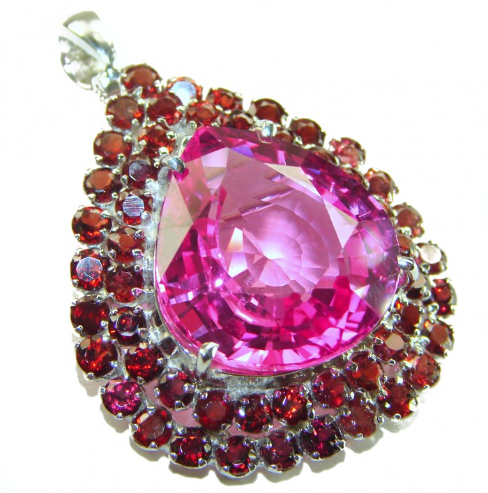 Penelope - 19.5 carat Pink Sapphire .925 Sterling Silver handmade Pendant Brooch - Close-up of pink sapphire pendant surrounded by red stones in silver setting.