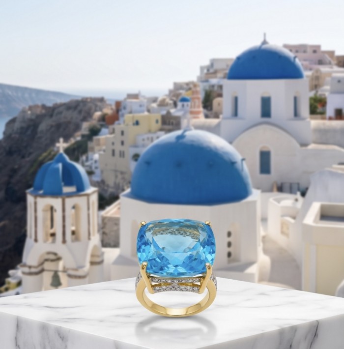 Paradise 35.8 carat Swiss Blue Topaz .925 Sterling Silver dipped in 22K Gold handmade Large Statement Ring size 6 - Close-up of Swiss Blue Topaz ring with Santorini backdrop.