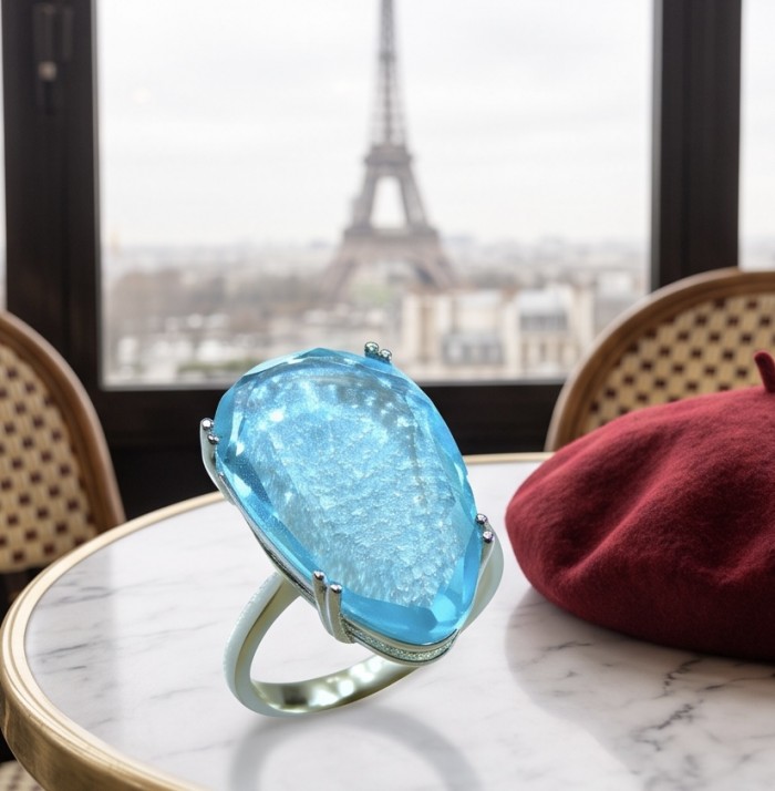 Massive Deep Blue 21.8 carat Aquamarine .925 Sterling Silver handcrafted ring size 7 1/4 - Close-up of massive blue aquamarine ring on table with Eiffel Tower view.