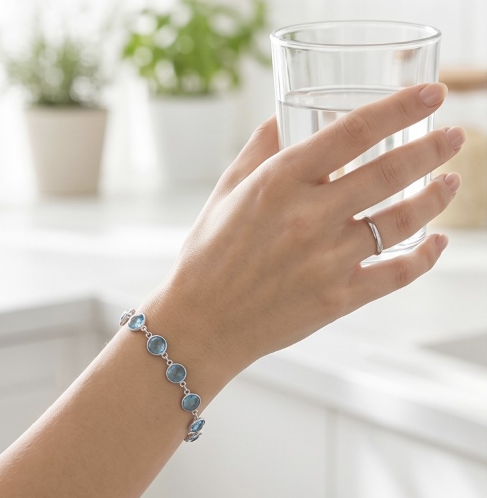 Authentic 10.5 carat Swiss Blue Topaz .925 Sterling Silver handmade Bracelet - Bracelet worn on hand holding a glass of water in kitchen setting.