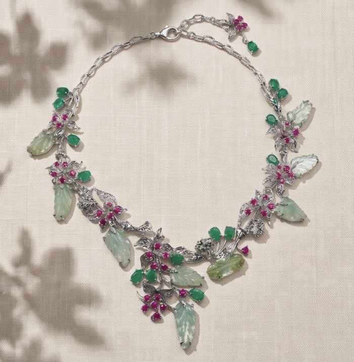 RARE BEAUTY! Valentina 168.2 carat CARVED Green Amethyst .925 Sterling Silver dipped in rhodium Statement Necklace - Ornate necklace with carved green stones, top view on textured background.