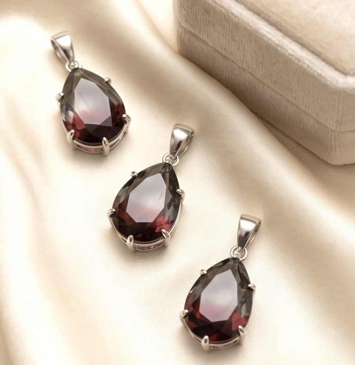 From dawn to dusk authentic 11.2 carat Brazilian Smoky Topaz .925 Sterling Silver Perfectly handcrafted pendant - Close-up of three teardrop smoky topaz pendants on satin fabric