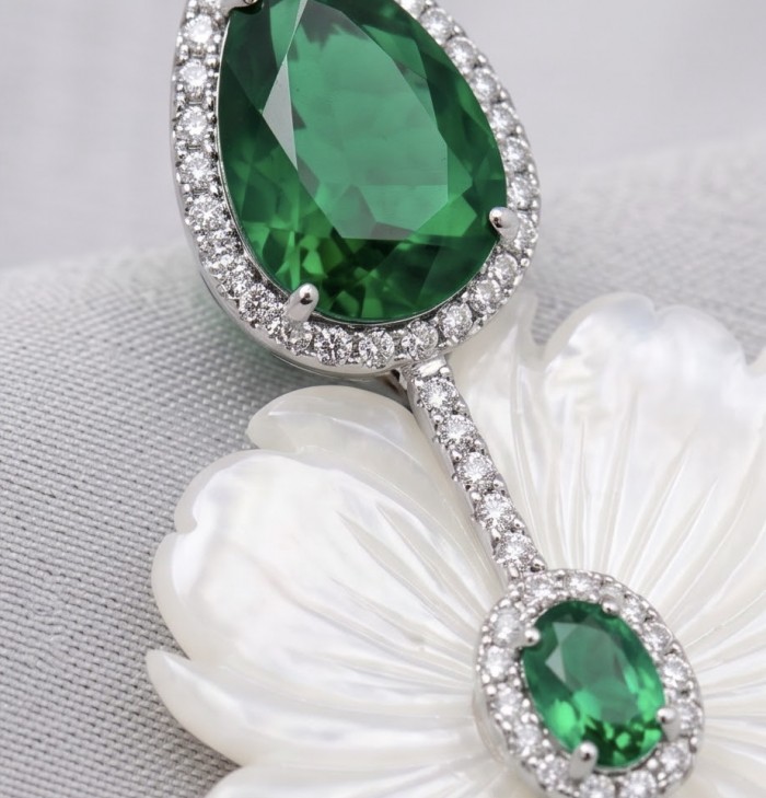 Summer Flowers Blister Pearl Blue Topaz Rhodium over .925 Sterling Silver handcrafted Earrings - Close-up of emerald pendant with diamond accents on pearl background.