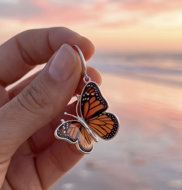 Butterflies carved Baltic Polish Amber 18K Gold over .925 Sterling Silver handcrafted earrings - Butterfly amber necklace close-up, held against a beach sunset background.