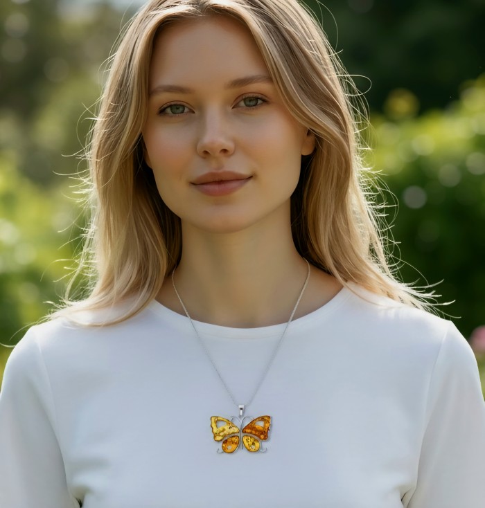 Golden Butterfly Authentic carved Baltic Amber .925 Sterling Silver handcrafted pendant - Butterfly amber pendant worn by model, front view, outdoors.