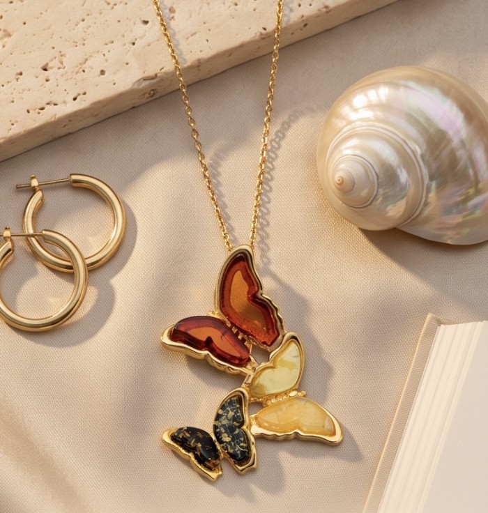 Golden Butterflies Authentic carved Baltic Amber 18K Gold over .925 Sterling Silver handcrafted pendant - Butterfly amber necklace and hoop earrings on fabric and shell background.