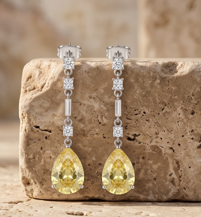 Luxurious pear cut 8.5 carat Yellow Sapphire rhodium over .925 Sterling Silver handcrafted earrings - Yellow Sapphire earrings, front view, on stone background.