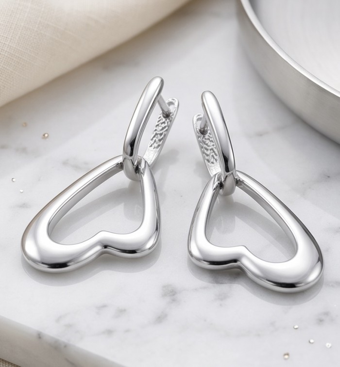 Hearts - 925 Sterling Silver luxuriously dipped in rhodium handmade earrings - Heart-shaped silver earrings, side angle on marble surface.