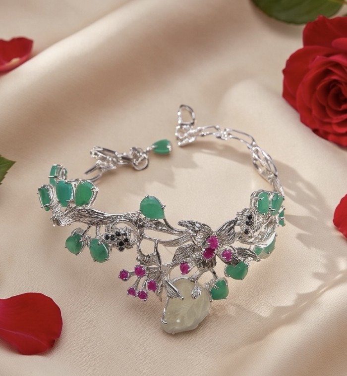 RARE BEAUTY! Valentina 58.2 carat CARVED Green Amethyst .925 Sterling Silver dipped in rhodium Statement handcrafted Bracelet - Side view of intricate bracelet with green and red gemstones on fabric.