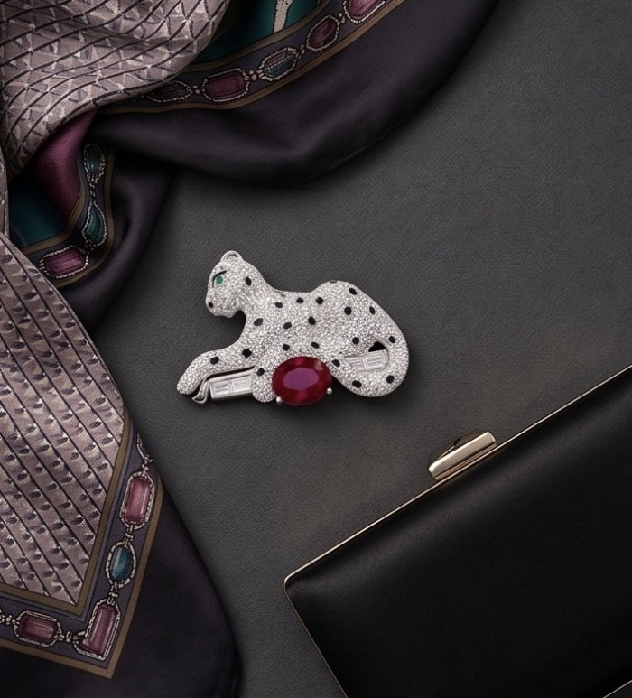 Precious Cheetah authentic 7.4 carat Ruby .925 Sterling Silver Handcrafted pendant brooch - Cheetah brooch with ruby, side view, on fabric and near a black clutch.