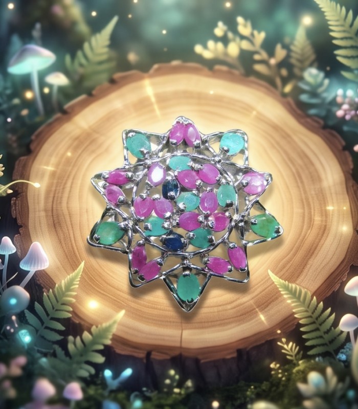 20.5 carat Authentic Kashmir Ruby Emerald Sapphire .925 Sterling Silver handcrafted Pendant and Brooch - Top view of gemstone brooch on wood surrounded by fantasy foliage.