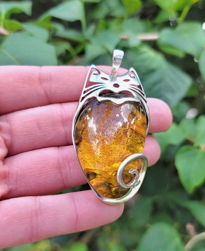 Tomcat 30.9 grams Prehistoric Authentic Baltic Amber .925 Sterling Silver beautifully handcrafted Large Pendant - Close-up of cat-shaped Baltic amber pendant in hand, silver details visible.